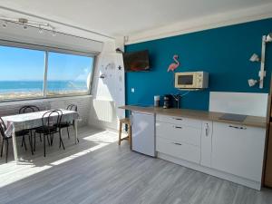 eine Küche mit einem Tisch und ein Esszimmer mit einem Fenster in der Unterkunft Studio front de mer avec vue mer panoramique ! in Le Grau-du-Roi
