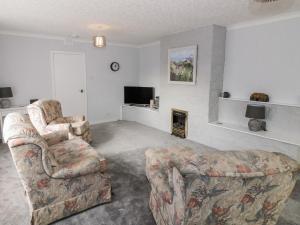 a living room with two chairs and a television at Honesty Cottage in Girvan