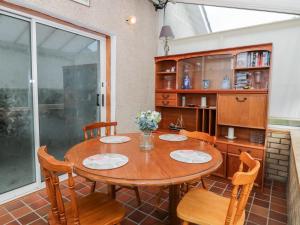 a dining room with a wooden table and chairs at Honesty Cottage in Girvan