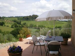 eine Terrasse mit einem Tisch, Stühlen und einem Sonnenschirm in der Unterkunft Fullino Nero Rta - Residenza Turistico Alberghiera in Siena