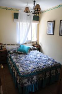 a bedroom with a bed with a blue comforter and a window at Casas Rurales Tiscar in Arroyo Frio