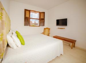 a bedroom with a white bed and a flat screen tv at Bioma Boutique Hotel in Mompos