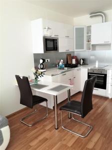 a kitchen with a table and two black chairs at New apartment with garage parking in Brno