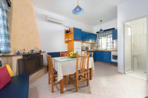 a kitchen with blue cabinets and a table and chairs at Stegna Sunny-Beach in Archangelos