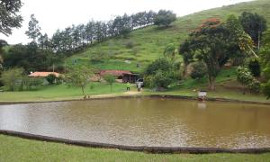 einen Teich auf einem Feld mit einem Hügel im Hintergrund in der Unterkunft Sitio Cantinho Verde Cedro in Cunha