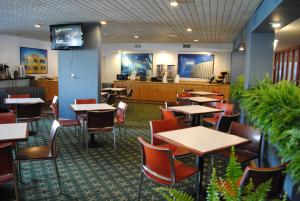 una sala da pranzo con tavoli e sedie e una cucina di Floridian Hotel a Homestead