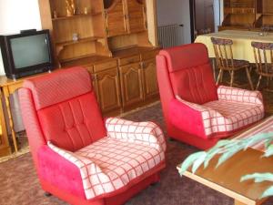 two red chairs and a tv in a living room at Rekreacny dom Altwaldorf Vysoke Tatry in Stará Lesná