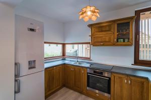 eine Küche mit Holzschränken und einem weißen Kühlschrank in der Unterkunft Pensiunea Agroturisticā Lukács Panzió in Ujfalù