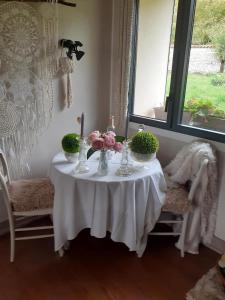 ein weißer Tisch mit Blumen in Vasen darauf in der Unterkunft Chez Martine in Hanc