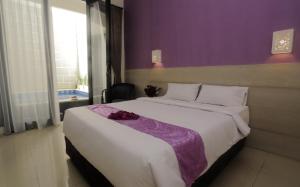 a bedroom with a large bed with a purple wall at Bali Dream Costel in Denpasar