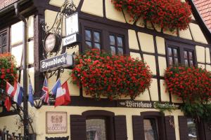 un edificio con flores rojas a un lado. en Spundloch- das Hotel & Weinrestaurant, en Veitshöchheim