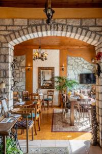 una sala da pranzo con tavoli, sedie e un muro in pietra di Semeli Guesthouse a Karpenision