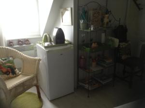 a room with a refrigerator and a chair and a shelf at Le Jardin des Poules in Thiétreville