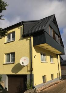 ein gelbes Haus mit schwarzem Dach in der Unterkunft Ferienwohnung Rolf in Crottendorf