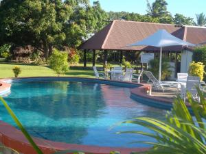 a swimming pool with chairs and an umbrella at Gecko's Resort in Sigatoka