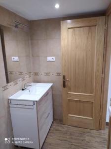 ein Badezimmer mit einem Waschbecken und einer Holztür in der Unterkunft EL MEJICANO II in Trevías