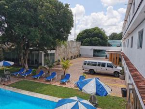 a car parked next to a pool with blue chairs and umbrellas at Hotel Las Dalias Inn in M&eacute;rida