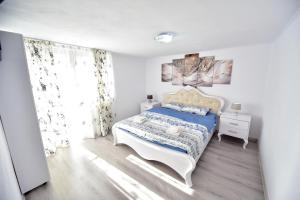 a white bedroom with a bed and a window at Casa Hanea & SPA piscina exterioara incalzita ,sauna, jacuzzi privat in fiecare apartament in Sibiu