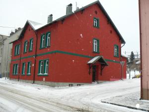 een groot rood gebouw met sneeuw op de grond bij Penzion Na Vápence in Liberec