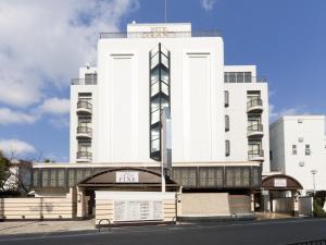 um edifício branco com um sinal em frente em Hotel Grand Fine Toyonaka Minami em Toyonaka