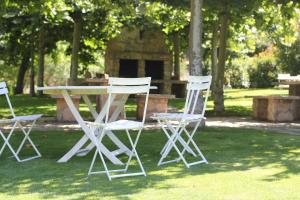 tres sillas blancas y una mesa en el césped en Hotel Ribera del Corneja, en Navacepedilla de Corneja