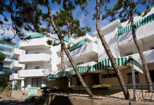 a white apartment building with green and white balconies at Hotel Garden in Lignano Sabbiadoro