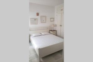 a white bedroom with a bed and a cabinet at Apartamento Las Infantas. Centro de Sanlucar. in Sanlúcar de Barrameda