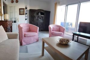 a living room with pink chairs and a table at Apartamento Las Infantas. Centro de Sanlucar. in Sanlúcar de Barrameda