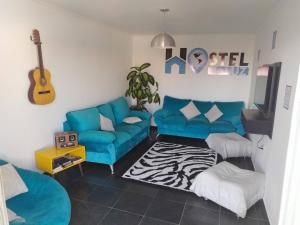 uma sala de estar com um sofá azul e uma guitarra em Hostel de Luz - Unidade 1 em Campinas