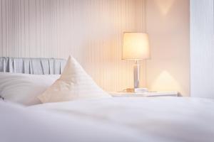 una cama blanca con una lámpara en una mesa lateral en Hotel Spies, en Gladenbach