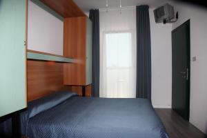 Un dormitorio con una cama azul y una ventana en Hotel Garden, en Lignano Sabbiadoro