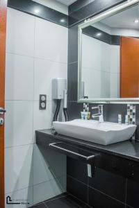 W łazience znajduje się biała umywalka i lustro. w obiekcie NOHO Boutique Koukaki , premium living w Atenach