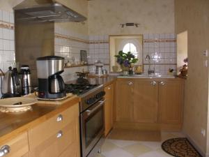 a kitchen with wooden cabinets and a stove top oven at Logis Saint Martin in Magny-lès-Villers