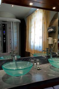 紹薩爾地區基策克的住宿－das kappel wein gut hotel，浴室里设有两个水槽,在柜台上放着绿色的碗