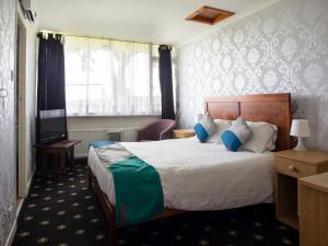 een hotelkamer met een bed en een televisie bij OYO Knowesgate Inn, Northumberland National Park in Kirkwhelpington