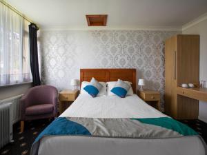een slaapkamer met een bed met blauwe kussens en een stoel bij OYO Knowesgate Inn, Northumberland National Park in Kirkwhelpington