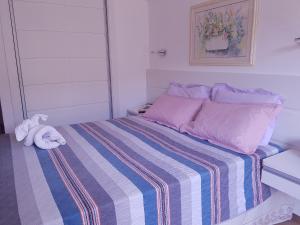 un letto con una coperta a righe e un peluche sopra di Hotel Cavalinho Branco Flat Service 615 ad Águas de Lindóia Altre 54 foto