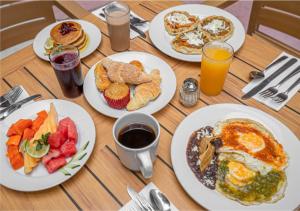 a wooden table with plates of breakfast foods and drinks at Playa Suites Acapulco in Acapulco