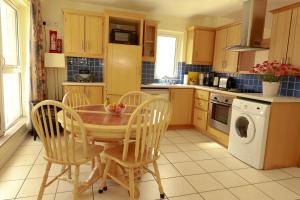 a kitchen with a wooden table and chairs and a washing machine at Arus Grattan in Galway