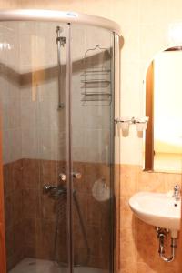 a shower with a glass door next to a sink at Eliza Apartment Sequoia in Borovets