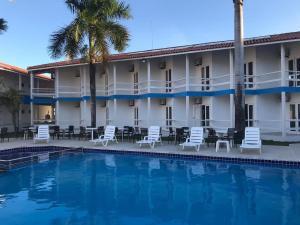 a hotel with a pool and chairs and palm trees at Sueds Segundo Sol in Santa Cruz Cabrália