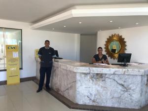 two men standing next to a marble counter in a lobby at Sueds Segundo Sol in Santa Cruz Cabrália