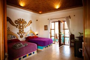 a bedroom with two beds with purple sheets and a mirror at Nacional Beach Club & Bungalows in Mahahual