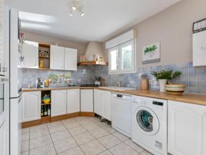 uma cozinha com armários brancos e uma máquina de lavar e secar roupa em House in the south of France with private pool em Roquebrun