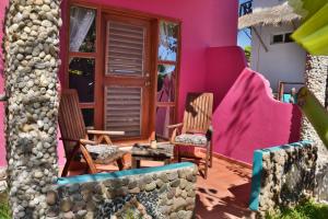 two chairs and a table outside of a pink house at Nacional Beach Club & Bungalows in Mahahual