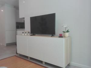 a television on a white cabinet in a living room at Eanes 22 beach house in Monte Gordo