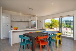 a kitchen with a wooden table and colorful chairs at Dune Views - Mangawhai Heads Holiday Home in Mangawhai