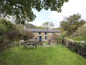 a stone house with a picnic table in front of it at Llwyn Bedw in Dinorwic