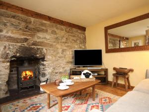 a living room with a fireplace and a tv at Llwyn Bedw in Dinorwic