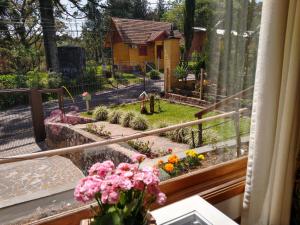 una ventana con vistas al jardín y flores en El Refugio 700, en Gramado